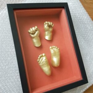 gouden hand en voet afdrukjes in zwarte lijst met rode binnenkant gemaakt